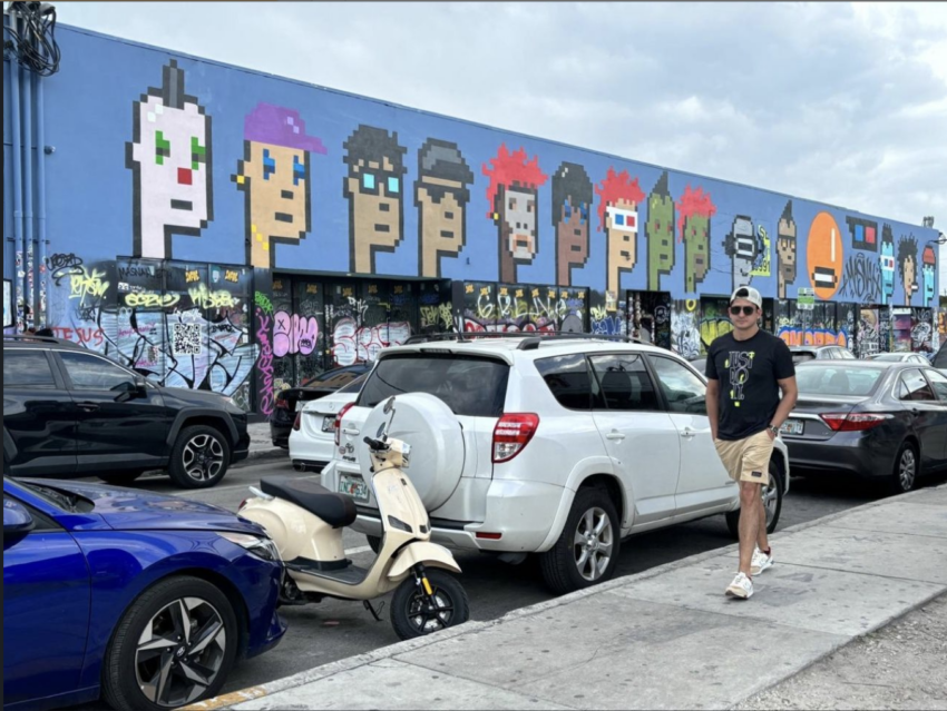 Eduardo Galvão caminhando em frente a famoso mural dos PUNK NFTs.